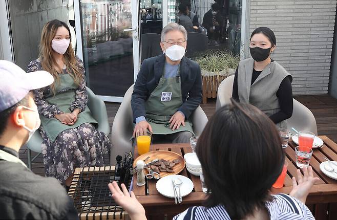 Democratic Party presidential nominee Lee Jae-myung speaks with young people at a shared housing facility for young people in Seoul’s Dongdaemun District on Saturday morning. (National Assembly pool photo)