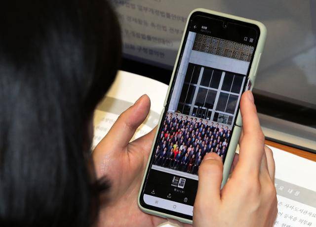 11일 오후 국회 본회의장에서 한 의원이 회의 직전 진행된 국회의원 단체 기념촬영 사진을 살펴보고 있다. 오대근 기자