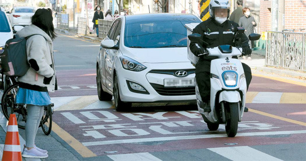 전면등교를 사흘 앞둔 19일 서울 시내 한 초등학교 앞에서 어린이가 횡단보도를 건너려고 기다리고 있지만 차량과 오토바이는 정지하지 않고 빠르게 통과하고 있다. [박형기 기자]