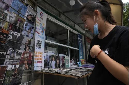 지난 9월1일 중국 베이징의 거리에서 한 여성이 아이돌 그룹 엑소의 전 멤버인 크리스가 표지에 실린 연예잡지 등이 진열된 신문 가판대를 쳐다보고 있다. 베이징=AP연합