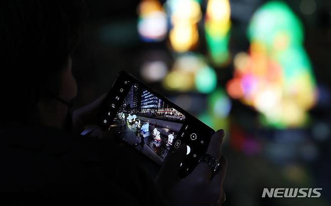 [서울=뉴시스] 홍효식 기자 = 2021 서울빛초롱축제를 하루 앞둔 25일 오후 서울 중구 청계천에서 한 시민이 형형색색의 조형물들을 담고 있다. 이번 축제는 26일부터 다음 달 5일까지 열흘간 청계천 일대에서 열린다. 2021.11.25. yesphoto@newsis.com