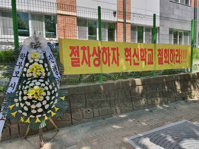 경기지역 한 초등학교 앞에 혁신학교 추진 결정에 반대하는 학부모들이 내걸은 현수막과 조화가 놓여있는 모습. ※기사와 무관 *재판매 및 DB 금지