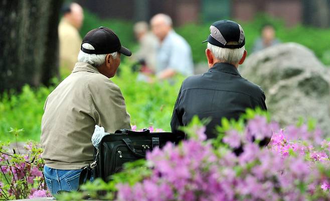 Senior citizens sit on a bench in a park in Seoul. (The Korea Herald)