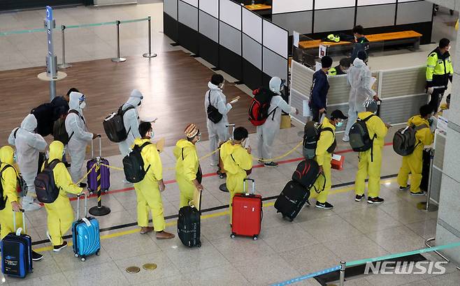 [인천공항=뉴시스] 배훈식 기자 = 코로나19 변이 바이러스 오미크론 유입 차단을 위해 남아공 등 8개국 발 외국인 입국이 제한된 29일 오전 인천국제공항 제1터미널에서 방호복을 착용하고 입국한 외국인들이 행선지 이동 수단 등을 확인하기 위해 대기하고 있다. 2021.11.29. dahora83@newsis.com