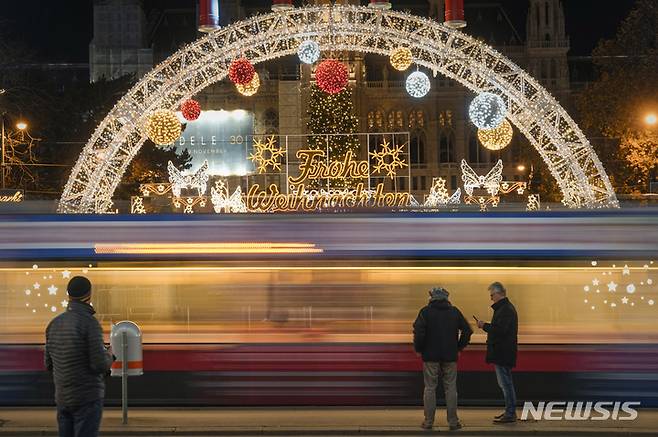 [빈=AP/뉴시스] 지난달 23일(현지시간) 오스트리아 수도 빈에서 시민들이 코로나19로 폐쇄된 크리스마스 마켓을 배경으로 트램을 기다리고 있다. 2021.12.01.