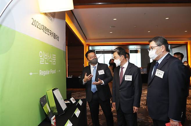 지난 2일 서울 여의도 콘래드 서울에서 열린 2021 대한민국 식품대상 시상식에서 일반식품·가공식품 심사위원장을 맡은 문정훈(맨 왼쪽) 서울대 교수가 김태흠(가운데) 국회 농림축산식품해양수산위원장과 김영수 조선비즈 대표 등 관계자에게 올해 최고의 식품으로 선정된 풀무원식품의 노을해심 김을 소개하고 있다. /조선비즈