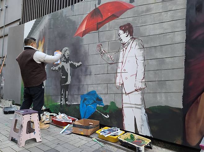 5일 오후 1시, 서울 종로구 관철동의 한 중고서점 벽면에 그래피티 작가 '탱크시'가 국민의힘 윤석열 후보를 소년에게 우산을 씌워주고 있는 모습으로 표현하고 있다. /채제우 기자