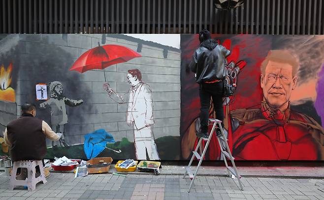 보수와 진보성향 탱크시(왼쪽), 닌볼트 그래비티 작가가 12월 5일 오후 서울 종로구의 한 중고서점 외벽에 각각 이재명 더불어민주당 대선 후보와 윤석열 국민의힘 대선후보의 벽화를 그리며 아트배틀을 펼치고 있다. /뉴시스
