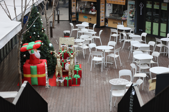 Tables and chairs are empty at an outdoor eating area in Sinchon Boxquare, a complex for restaurants in Seodaemun District, western Seoul, on Monday. Visitors to restaurants have been decreasing due to rising Covid-19 cases and new rules limiting people to eat in groups of six or less. [YONHAP]