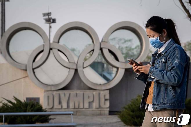 중국 베이징 국립경기장 앞에 설치돼 있는 오륜 조각상을 한 여성이 지나가고 있다. © AFP=뉴스1