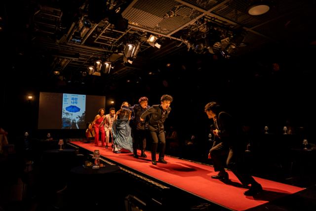 연극 '김수정입니다'는 시상식 무대처럼 양 끝 무대를 연결하는 복도식 무대를 십분 활용한다. 배우들이 무대에 일렬로 서서 연기하는 모습. 두산아트센터 제공