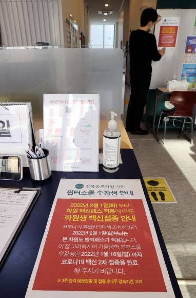 학원 방역패스 적용에 따른 안내문 - 7일 서울 마포구 종로학원 강북본원에서 직원이 방역패스 관련 안내문을 부착하고 있다.      정부가 학생과 학부모들의 반발에도 내년 2월부터 식당?카페?학원?도서관 등을 이용하는 12~18세 청소년에게도 방역패스를 적용한다고 밝히면서, 학생과 학부모들을 중심으로 ‘미접종자에 대한 차별이자 학습권 침해, 사실상 접종 강요’라는 움직임이 거세지고 있다. 2021.12.7 연합뉴스