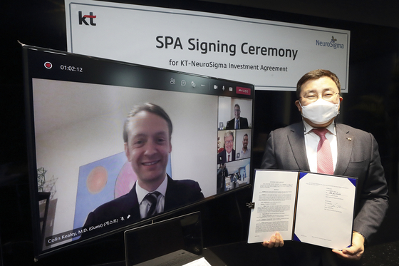 Song Jae-ho, vice president of KT's AI/DX division, holds the business agreement contract with NeuroSigma, on Wednesday next to a screen showing Colin Kealey, vice president of NeuroSigma. KT has invested $5 million in Los Angeles-based NeuroSigma, whose digital treatment for attention deficit hyperactivity disorder (ADHD) has been approved by the U.S. Food and Drug Administration (FDA). [KT]