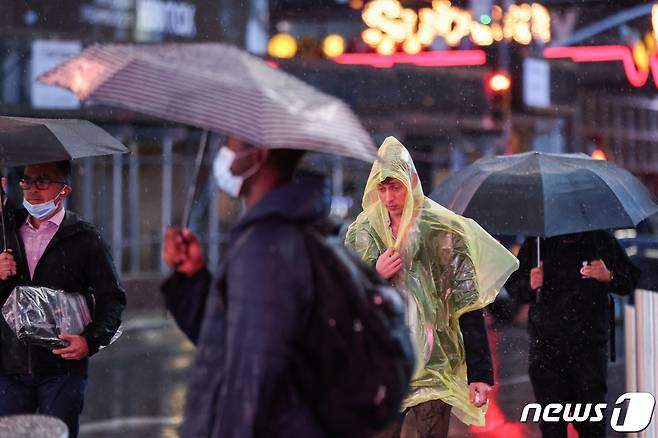 지난 달 26일 미국 뉴욕주 맨해튼에서 시민들이 마스크를 쓴 채 비오는 거리를 걷고 있다. © 로이터=뉴스1 © News1 노선웅 기자