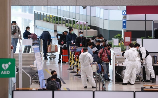 인천국제공항 제1여객터미널 입국장에서 신종 변이 오미크론의 확산에 따른 입국자 격리 조치 시행으로 입국한 외국인들이 공항 방역 관계자로부터 격리시설로 이동하기 전 신원 확인을 하고 있는 모습. 사진=연합뉴스