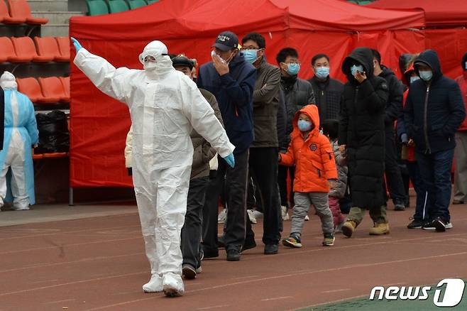 중국 톈진의 신종 코로나바이러스 감염증 진단 검사소를 찾은 시민들이 마스크를 착용한 채 한 줄로 서서 방역관 지시를 따르고 있다. 2020.11.21 © AFP=뉴스1