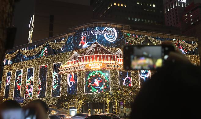 14일 오후 서울 명동 신세계백화점 본점 외벽에 설치된 미디어 파사드를 한 시민이 촬영하고 있다./연합뉴스