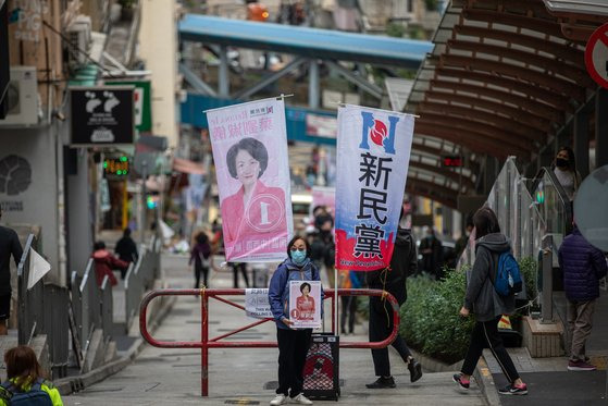 홍콩 입법회 선거가 치러진 19일 한 선거 운동원이 후보 포스터를 들고 투표를 독려하고 있다. 1년 연기돼 치러진 이번 선거는 ‘애국자가 홍콩을 다스린다’는 원칙에 따라 출마자의 사전 심사 강화, 직접 선출 의원 수 축소 등으로 민주파가 불참해 친중·친정부 후보로만 치러졌다. [EPA=연합뉴스]