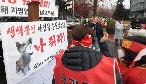 지난 16일 오후 경남 창원시 성산구 경남도청광장 교차로 앞 도로에서 열린 '코로나19 피해 실질 보상 촉구 정부·여당 규탄대회'에서 참가자들이 동전을 던지며 손실보상금을 비판하고 있다. 연합뉴스