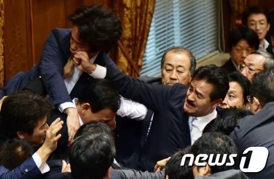 2015년 당시 일본 안보 법제 제·개정안 날치기 통과를 주도한 자민당의 사토 마사히사 참의원이 주먹으로 민주당 소속의 고니시 히로유키(小西洋之, 왼쪽) 의원의 얼굴을 밀어내고 있다. © 뉴스1