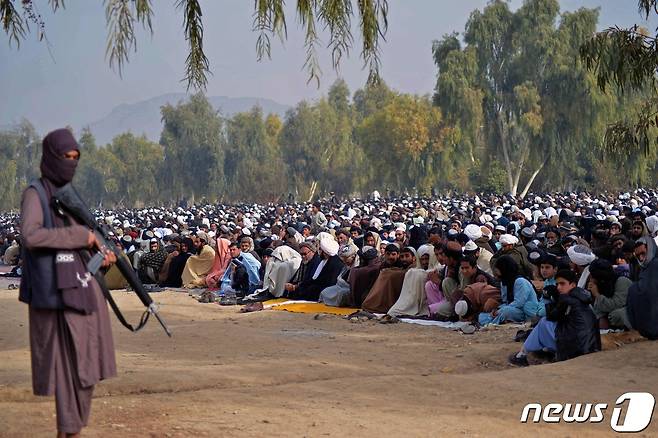아프간인들이 2021년 12월 25일(현지시간) 칸다하르의 아이다에서 기우제를 준비하고 있는 가운데 탈레반군(왼쪽)이 경계를 서고 있다. © AFP=뉴스1 © News1 김지현 기자