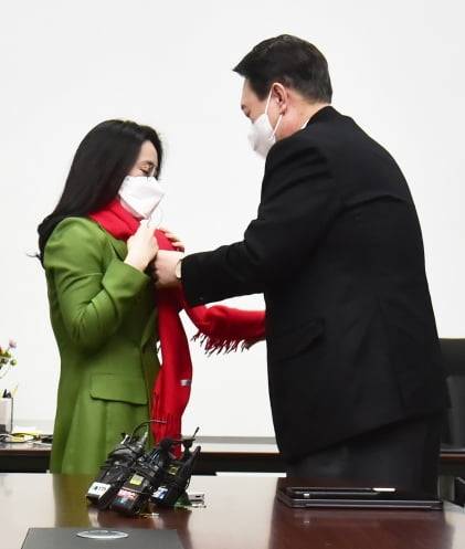 윤석열 국민의힘 대선 후보가 20일 서울 여의도 새시대준비위원회 위원장실에서 열린 영입인사 환영식에서 신지예 한국여성정치 네트워크 대표에게 환영 목도리를 걸어주고 있다. 뉴스1
