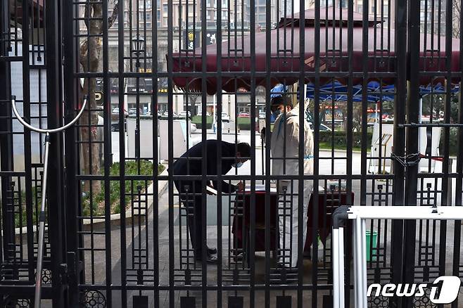 중국 시안에서 코로나19 집단 감염에 따라 고강도 봉쇄 정책이 실시 중인 가운데, 2021년 12월 23일  주거 지역 입구에 보안원이 지켜서서 주민 출입 정보를 받고 있다.  © AFP=뉴스1