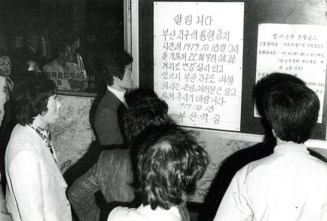 1979년 10월 18일 통금 연장에 따라 열차운행 시간이 변경됐음을 알리는 공고문이 나붙은 부산역 대합실. 역에 나온 시민들이 공고문을 읽고 있다. 박정희 정권은 부마항쟁으로 부산지역의 통금 시간을 연장했다. 1979.10.18. 한국일보 자료사진