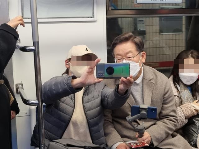 이재명 후보가 7일 서울 지하철을 타고 유튜브 라이브 방송을 진행하며 한 시민과 사진을 찍고 있다. 민주당 제공