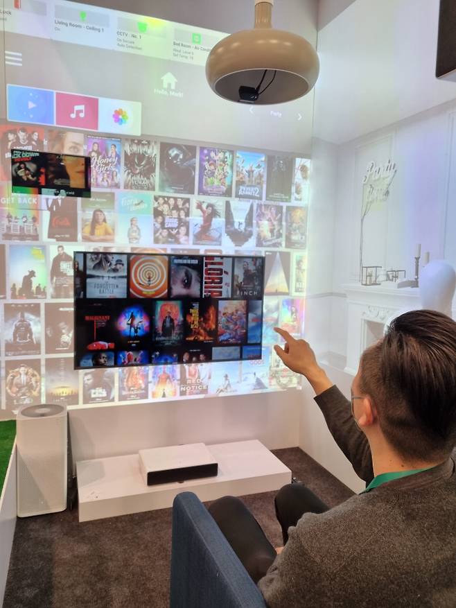 김석중 브이터치 공동대표가 6일(현지시간) 미국 라스베이거스컨벤션센터(LVCC) 센트럴홀에 있는 ‘CES 2022’ 부스에서 손가락으로 화면을 옆으로 넘기며 원하는 콘텐츠를 고르고 있다. 회색 등에 부착된 검은색 센서가 손가락과 시선을 인식한다. 이 센서와 TV, 공기청정기 등 가전기기들이 모두 와이파이로 연결된 상태에서 작동한다. 사진 상단에 연결된 기기들의 목록이 보인다.