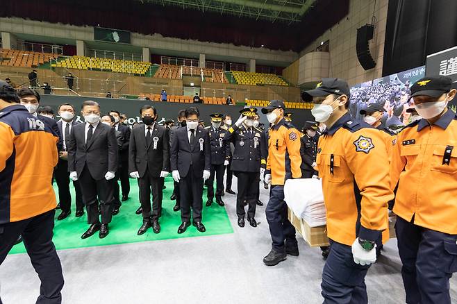 [평택=뉴시스]  8일 오전 평택 이충문화체육센터에서 경기도청장으로 마련된 故 이형석 소방경(50), 故 박수동 소방장(31), 故 조우찬 소방교(25)의 합동 영결식에서 문재인 대통령과 오병권 경기도지사 권한대행(장의위원회 위원장) 등 참석자들이 운구행렬을 향해 조의를 표하고 있다. (사진=경기도 제공) 2022.01.08. photo@newsis.com  *재판매 및 DB 금지