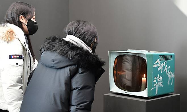 관람객들이 전시실 입구에 설치된 백남준의 촛불TV를 보고 있다.
