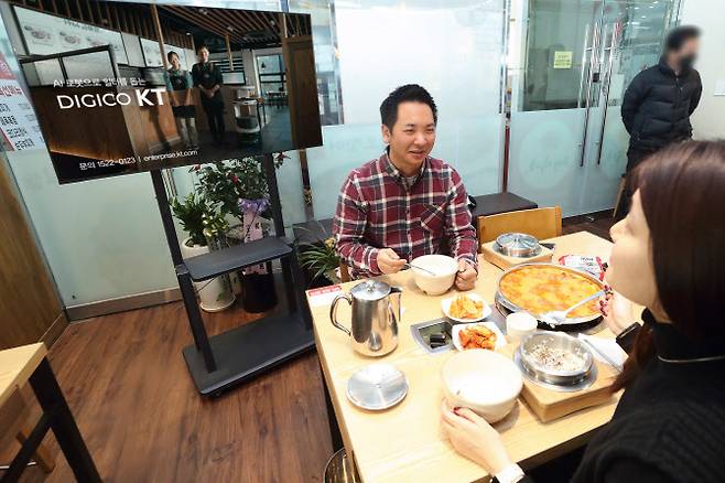 KT AI 서비스로봇 광고를 보고 있는 손님 모델