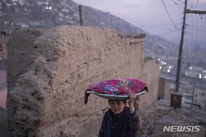 [카불=AP/뉴시스] 5일(현지시간) 아프가니스탄 카불에서 한 소년이 전통 빵이 담긴 쟁반을 머리에 이고 거리를 걷고 있다. 2021.12.06.