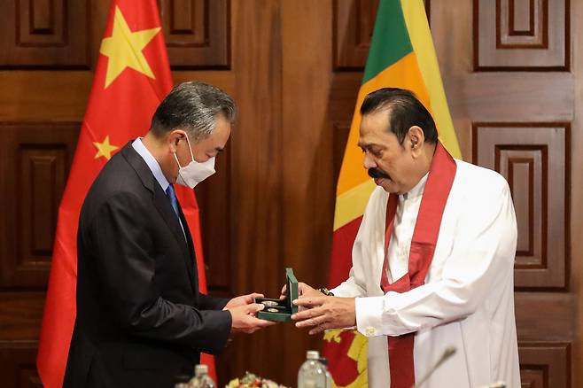 9일(현지 시각) 스리랑카 수도 콜롬보에서 마힌다 라자팍사(오른쪽) 스리랑카 총리가 왕이(왼쪽) 중국 외교부장에게 기념품을 전달하고 있다./AP 연합뉴스