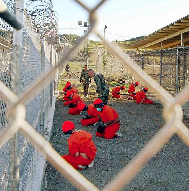 2002년 관타나모 기지 수감자들이 손이 묶이고 입에 재갈이 물린 채 미군의 감시를 받고 있다.  로이터연합뉴스