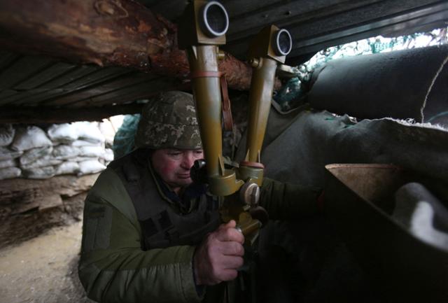 우크라이나 군인이 11일 러시아와의 접경 지역인 도네츠크주 지역 참호에서 망원경을 통해 경계 근무를 하고 있다. 도네츠크=AFP 연합뉴스