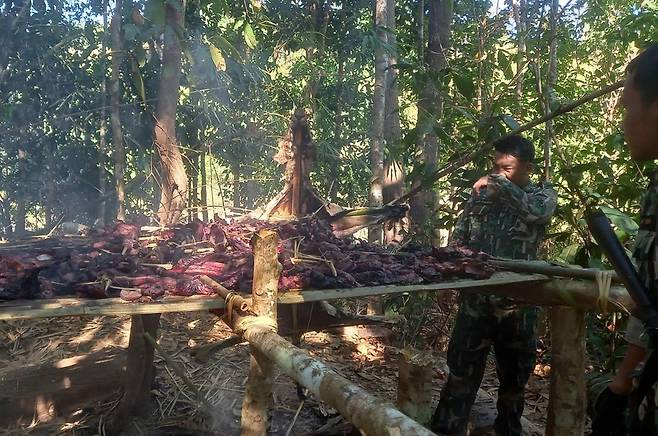 국립공원 순찰대가 모닥불 위에서 구워지고 있는 호랑이 고기를 살펴보는 모습. [Piyarat Chongcharoen 제공/방콕포스트 캡처. 재판매 및 DB 금지]