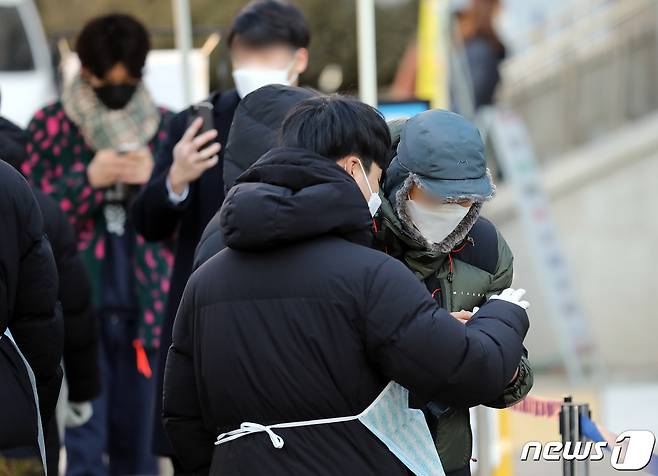 신종 코로나바이러스 감염증(코로나19) 신규 확진자가 4542명 발생한 14일 오전 서울 강서구 보건소에 마련된 선별진료소를 찾은 한 시민들이 검체검사를 받기 전 전자문진표를 작성하는 방법을 관계자에게 듣고 있다. 2022.1.14/뉴스1 © News1 김진환 기자