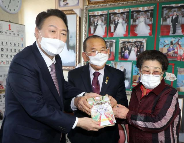 윤석열 국민의힘 대선후보가 14일 경남 창원시 마산합포구 신신예식장을 찾아 백낙삼, 최필순 부부와 기념촬영을 하고 있다. 부부는 신신예식장을 운영하며 55년간 신혼부부 1만4,000쌍에게 결혼식과 사진 촬영을 무료로 제공해왔다. 창원=뉴스1