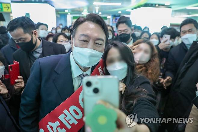 퇴근길 부산 시민들과 인사 나누는 윤석열 (부산=연합뉴스) 국민의힘 윤석열 대선 후보가 14일 오후 부산 도시철도 서면역에서 퇴근길 시민들과 인사하며 셀카를 찍고 있다. 2022.1.14 [국민의힘 선대위 제공. 재판매 및 DB금지] uwg806@yna.co.kr