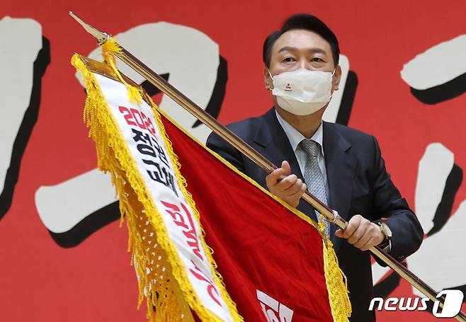 윤석열 국민의힘 대선 후보가 15일 오후 울산 동구 전하체육센터에서 열린 울산시 선거대책위원회 필승결의대회에 참석해 당 기를 받아들고 있다. 2022.1.15/뉴스1 © News1 구윤성 기자