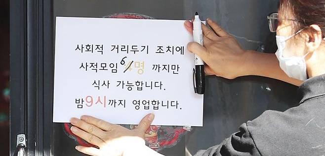 오늘부터 3주간 사적모임 6인까지 - 정부가 기존 사회적 거리 두기를 3주 더 연장하면서 16일 오후 서울 동작구 한 식당에 안내문이 붙어 있다. 17일부터 식당·카페 등에서 영업시간 제한은 밤 9시로 유지되지만, 모임 인원 제한은 4인에서 6인으로 다소 완화된다. /장련성 기자