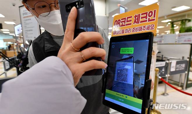 [광주=뉴시스] 변재훈 기자 = 대형 유통 점포 대상 방역패스(접종증명·음성확인제) 의무화 시행 첫 날인 10일 오전 광주 서구 한 대형마트에서 한 시민이 직원 안내를 받아 QR코드 출입 인증을 하고 있다. 2022.01.10. wisdom21@newsis.com