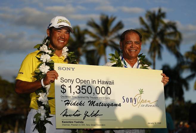 마쓰야마 히데키(왼쪽)가 17일 미국 하와이주 오아후섬의 와이알레이CC에서 열린 PGA 투어 최종라운드에서 공동선두로 마친 뒤 연장 첫 홀에서 승리한 뒤 우승상금 135만 달러가 적힌 패널을 들고 기뻐하고 있다. ㅣ게티이미지