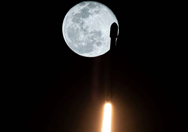 18일 49기의 스타링크 위성을 싣고 달을 배경 삼아 하늘로 날아오르는 팰컨9 로켓. 스페이스엑스 제공