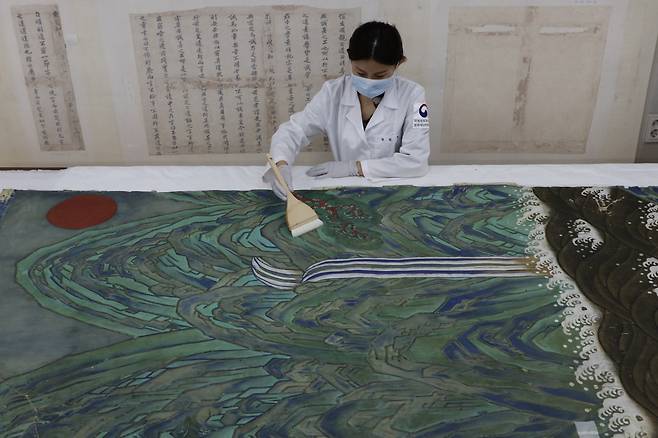 An art restorer demonstrates the cleaning process for the restoration of “Irworobongdo.” (CHA)