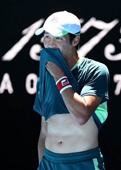 권순우가 19일 호주 멜버른에서 열린 호주오픈 테니스대회 남자 단식 2회전에서 데니스 샤포발로프에게 점수를 내준 뒤 힘에 부친 듯 상의를 끌어당겨 땀을 닦고 있다.멜버른 로이터 연합뉴스