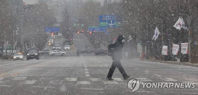 눈 내리는 출근길 (과천=연합뉴스) 한종찬 기자 = 서울을 비롯한 수도권과 충남북부에 대설주의보가 발효된 19일 오전 정부과천청사 앞에서 시민이 길을 건너고 있다. 2022.1.19 saba@yna.co.kr