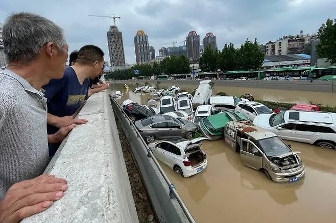 중국 허난성 정저우시 주민들이 지난해 7월 기록적인 폭우로 침수된 차량들을 바라보고 있다. AFP연합뉴스